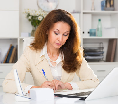 Female is working with documents and laptop