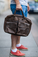 Young guy holds a leather bag in his hands