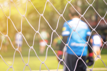 Fototapeta premium Soccor goal net with Asia school kids team playing football with young boys player in ball match field in sport club as background.