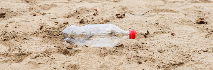 Discarded plastic water bottle lies in the sand on a beach