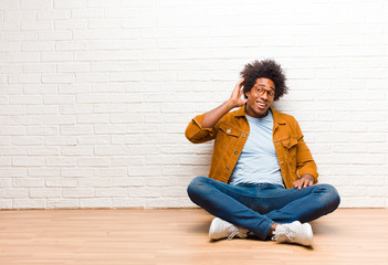 young black man looking serious and curious, listening, trying to hear a secret conversation or...