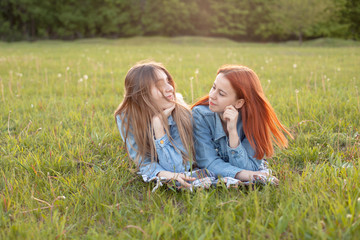 Fototapeta premium Two young women lie on the grass and look at each other. Best friends.