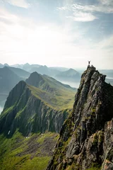 Gordijnen Adventurous man is standing on top of the mountain and enjoying the beautiful view during a vibrant sunset. Taken on top Senja, Norway  © Pavel Kašák