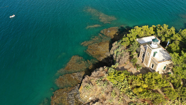 Aerial drone photo of lighthouse in tropical vegetated Mediterranean islet with beautiful sky and clouds