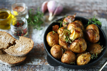 Rustic potato in a pan. Baked small potatoes in a peel with garlic and herbs. Selective focus. Macro.