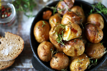 Rustic potato in a pan. Baked small potatoes in a peel with garlic and herbs. Selective focus. Macro.