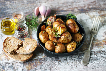 Rustic potato in a pan. Baked small potatoes in a peel with garlic and herbs. Selective focus....