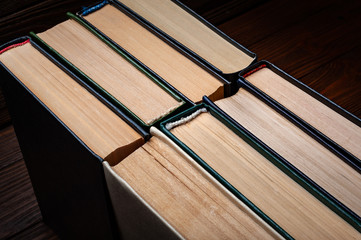 Old books . Old used closed hardback books in dust on dark wooden background.