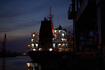 Colorful sunset over sea port and industrial cranes. Bright sunset in seaport. Large silhouettes of...