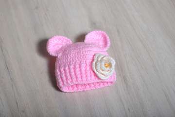 Cute children's knitted hat with ears like a mouse on a white carpet, close-up. Hat for newborns