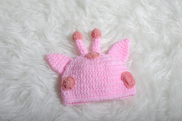 Cute children's knitted hat with ears and horns on a white carpet background, close-up