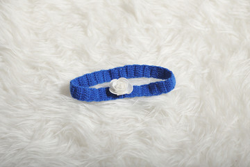 Cute children's knitted bandage strip of blue on a white carpet background, close-up