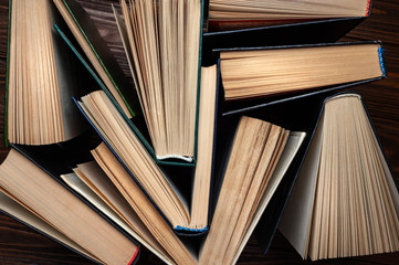 Naklejka premium Old books . Top view of several old used open hardback books in dust on a dark wooden background.