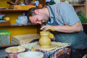 Professional male potter working with clay on potter's wheel