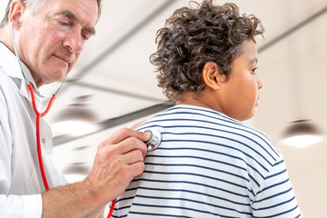 Close up of teen boy and doctor with stethoscope listening to heartbeat