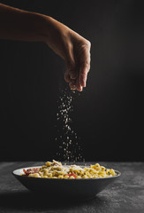 Close-up person putting cheese on pasta