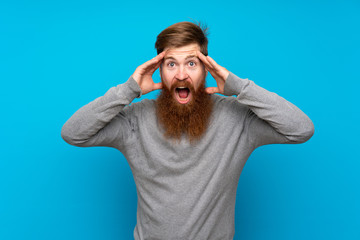 Redhead man with long beard over isolated blue background with surprise expression