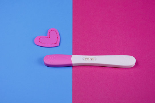 Positive pregnancy test stock images. Pregnancy test on a pink blue background. Positive pregnancy test with heart