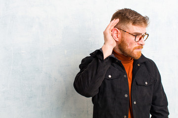 young red head man looking serious and curious, listening, trying to hear a secret conversation or...
