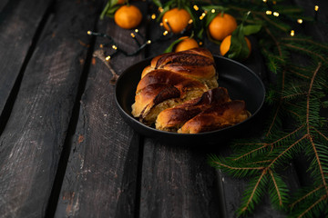 chocolate babka bread, dessert, on a dark wooden backdrop, tangerines and Christmas lights, black plate, rustic style