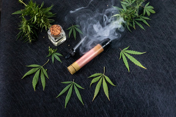Cannabis liquid. Vape CBD or THC, Vaping Marijuana Leaves and Hemp. On a dark background. Cloud of...