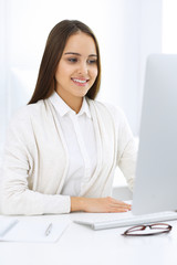 Business woman sitting and working with computer in white office. Student girl studying or secretary making report. Success concept