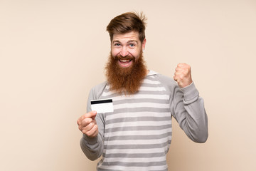 Fototapeta premium Redhead man with long beard over isolated background holding a credit card