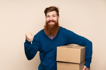 Redhead man with long beard over isolated background holding a box to move it to another site