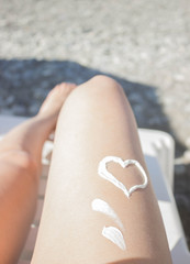 women's legs on the beach, smeared with protective cream, preparation for sunburn