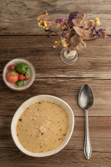 a bowl of homemade soup and fresh peppers on a wooden table