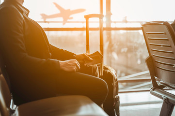Closeup a business male sitting with a passport while waiting to check in for boarding with luggage...