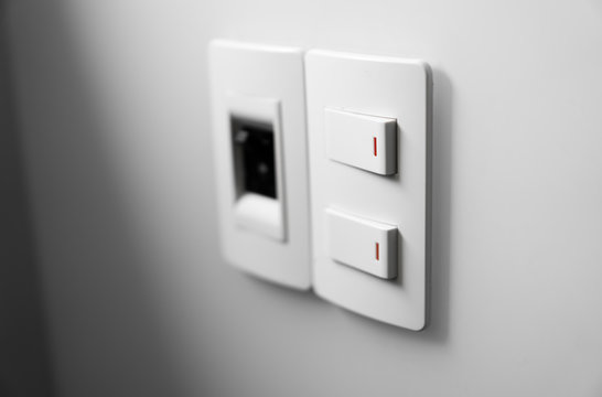 White switch on a white wall with two switches and one common switch.