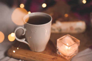 Cup of fresh black tea with burning candle stay on wooden tray closeup. Good morning. Autumn season.
