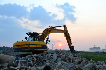 Excavator with crusher bucket for crushing concrete. Construction waste recycling for construction mix. Sifting and grinding bucket for the separation of concrete into fractions of higher quality.