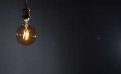 Beautiful large round retro lamp with incandescent threads glows on a background of a gray wall,...