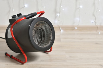 Round electric heat gun for heating the room against the background of a room and a garland