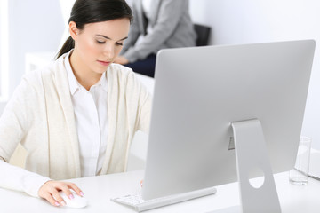 Business woman working with computer in office, female colleague at background. Headshot of Lawyer or accountant at work while sitting at the desk