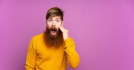 Obraz premium Redhead man with long beard over isolated purple background with surprise and shocked facial expression