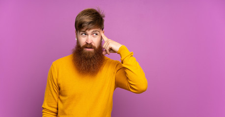 Redhead man with long beard over isolated purple background making the gesture of madness putting...