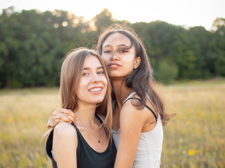 Two adorable young women hugging on the field. Best friends
