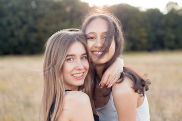 Two beautiful young women hugging outdoors at sunset. Best friends