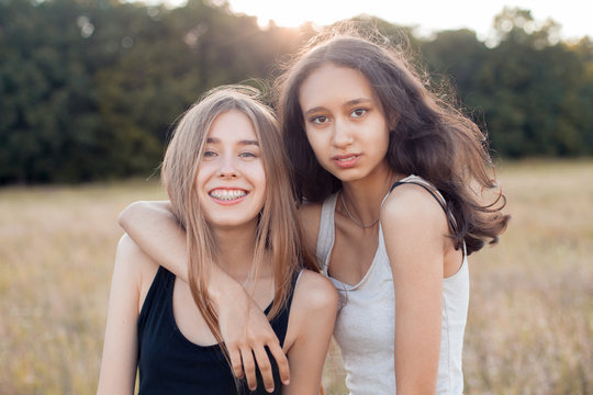 Two happy young women hugging outdoors at sunset. Best friends