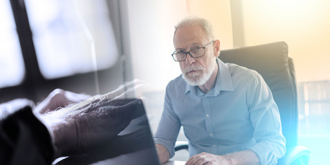 Portrait of senior businessman working on laptop; multiple exposure