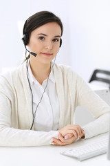 Call center. Beautiful woman receptionist sitting in headset at customer service office. Group of...