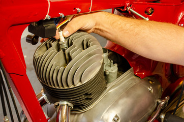A man hand dismount spark plug from old motorbike engine