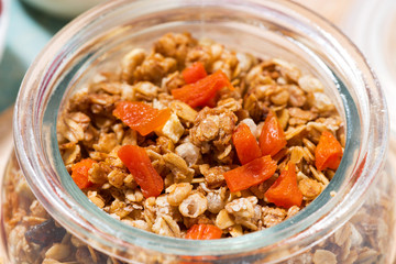 homemade granola with dried apricots and nuts in a jar, closeup