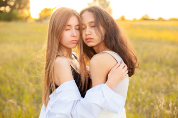 Fototapeta premium Two young women hugging outdoors at sunset
