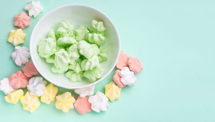 banner of pastel colored merengues cookies on mint green color background top view