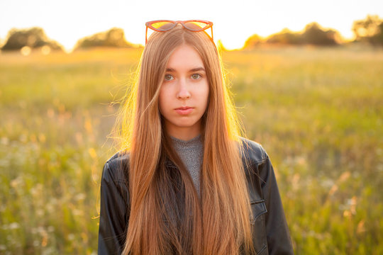 Young woman in leather jacket outdoors at sunset.