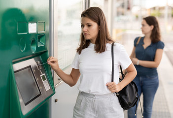 Fototapeta na wymiar Woman using ticket vending machine at tram stop